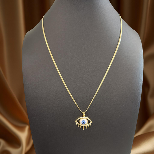 Gold necklace with an eye-shaped pendant on a mannequin against a brown satin background